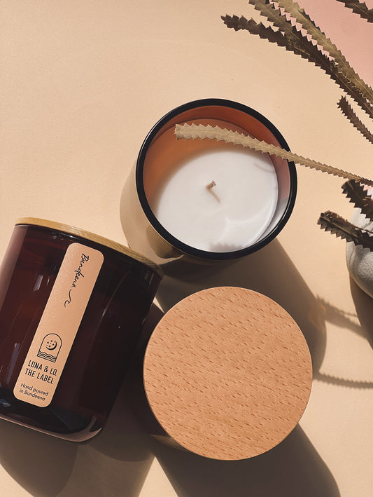 Candle with wooden lid on a beige surface with a cactus plant