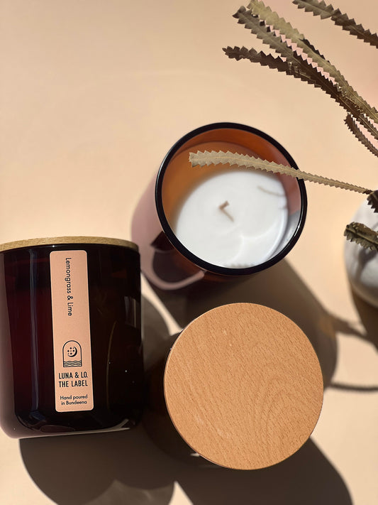 Candle with wooden lid and 'Luna & Lo The Label' packaging on a beige background